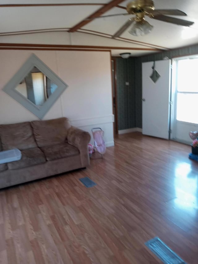 living room with a ceiling fan, vaulted ceiling, and wood finished floors