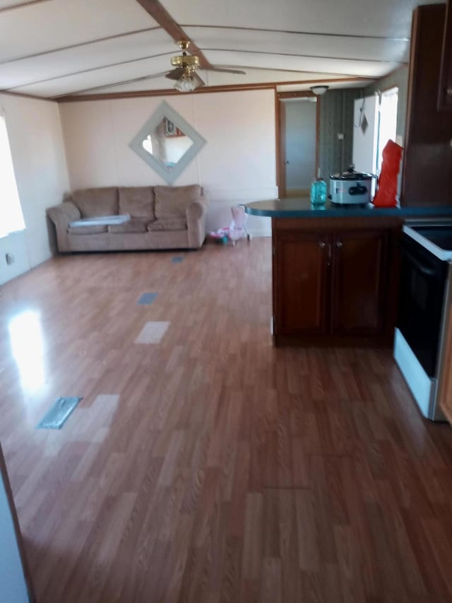 kitchen featuring wood finished floors, a peninsula, vaulted ceiling with beams, electric stove, and dark countertops