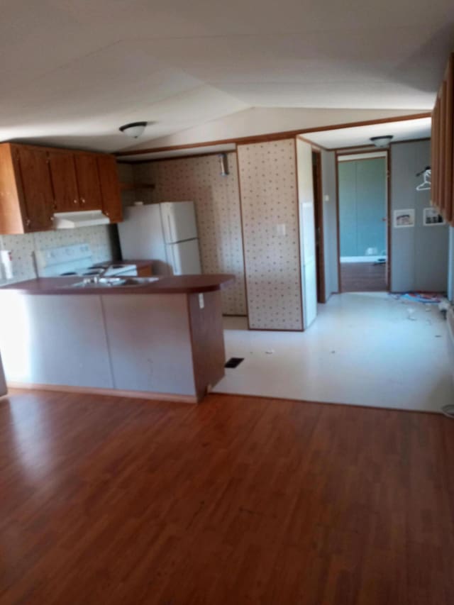 kitchen featuring brown cabinetry, light wood finished floors, freestanding refrigerator, stove, and under cabinet range hood