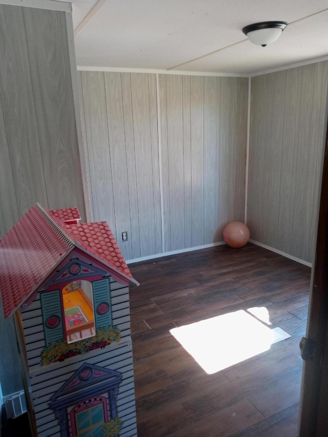 recreation room with baseboards, wood finished floors, and wood walls