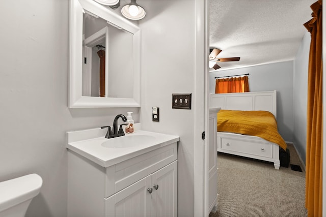 bathroom featuring vanity, ceiling fan, toilet, and a textured ceiling