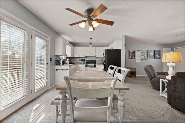 dining room with sink, light colored carpet, a textured ceiling, and ceiling fan