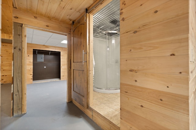 corridor featuring wooden walls and concrete flooring