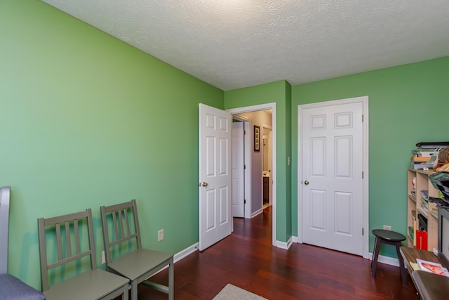 bedroom with a textured ceiling, baseboards, and wood finished floors