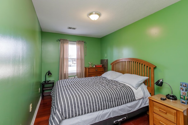 bedroom featuring visible vents, baseboards, and dark wood-style flooring