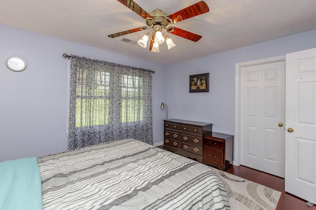 bedroom featuring a ceiling fan, wood finished floors, visible vents, and a textured ceiling