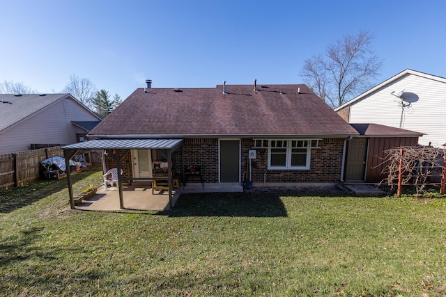 rear view of property with fence, brick siding, a lawn, and a patio area