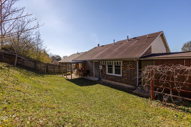 back of property with roof with shingles, a fenced backyard, a lawn, a patio area, and brick siding