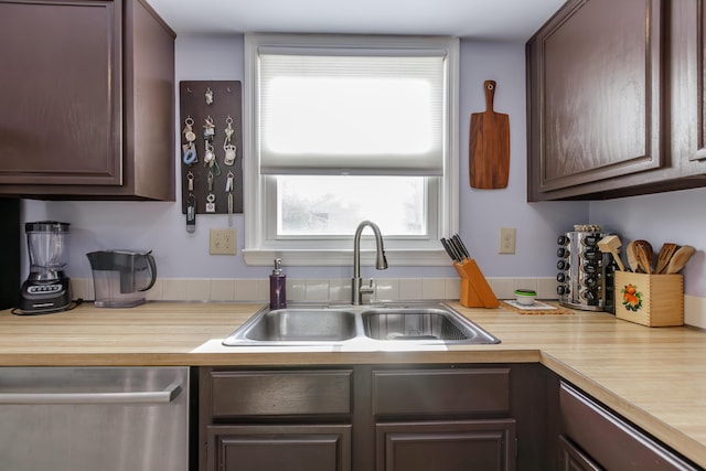 kitchen featuring dark brown cabinets, dishwasher, light countertops, and a sink