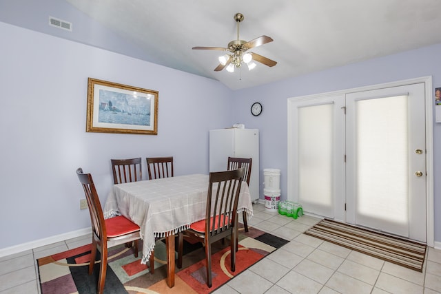 dining area featuring light tile patterned floors, a ceiling fan, visible vents, baseboards, and vaulted ceiling