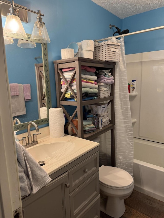 full bathroom featuring shower / bathtub combination with curtain, hardwood / wood-style floors, vanity, a textured ceiling, and toilet