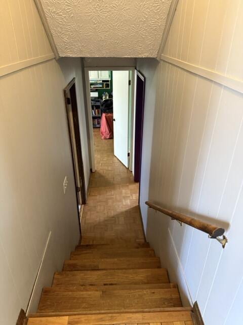 stairway featuring a textured ceiling