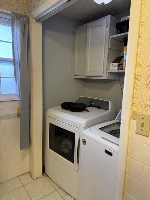 washroom with separate washer and dryer, cabinets, and light tile patterned flooring