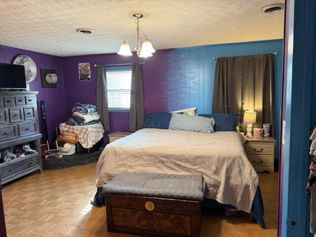 bedroom with a notable chandelier, parquet flooring, and a textured ceiling