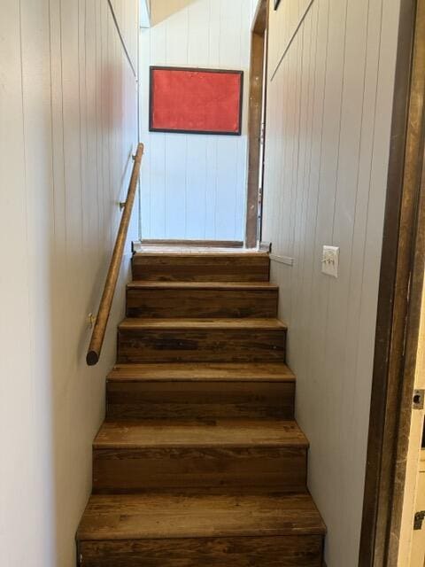 staircase with a barn door and wood walls