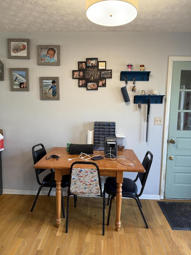 dining space with hardwood / wood-style floors and a textured ceiling