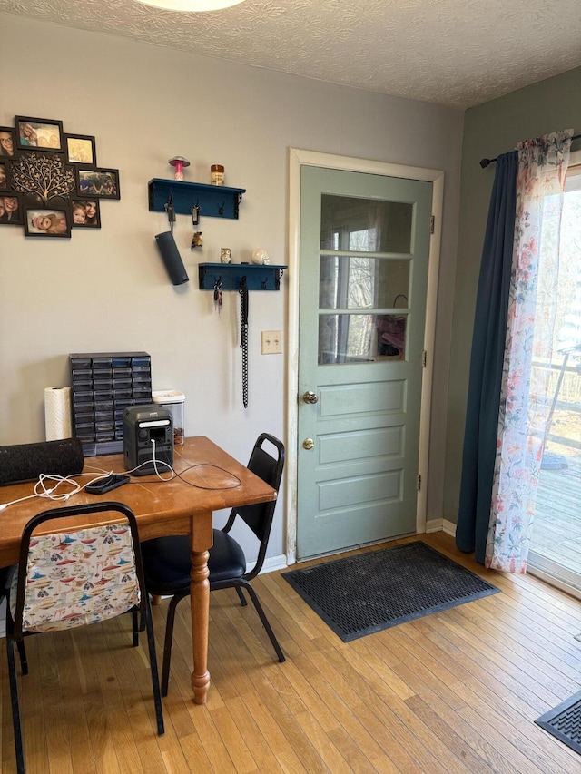 dining space with hardwood / wood-style flooring and a textured ceiling