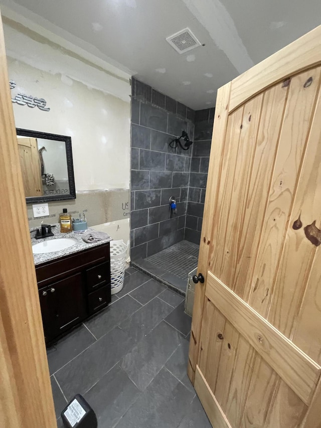 bathroom featuring vanity, tile walls, and tiled shower