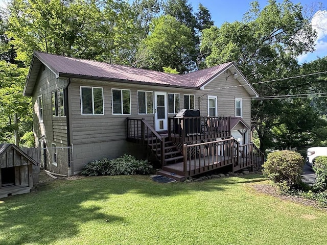 view of front facade with metal roof, a front yard, and a wooden deck