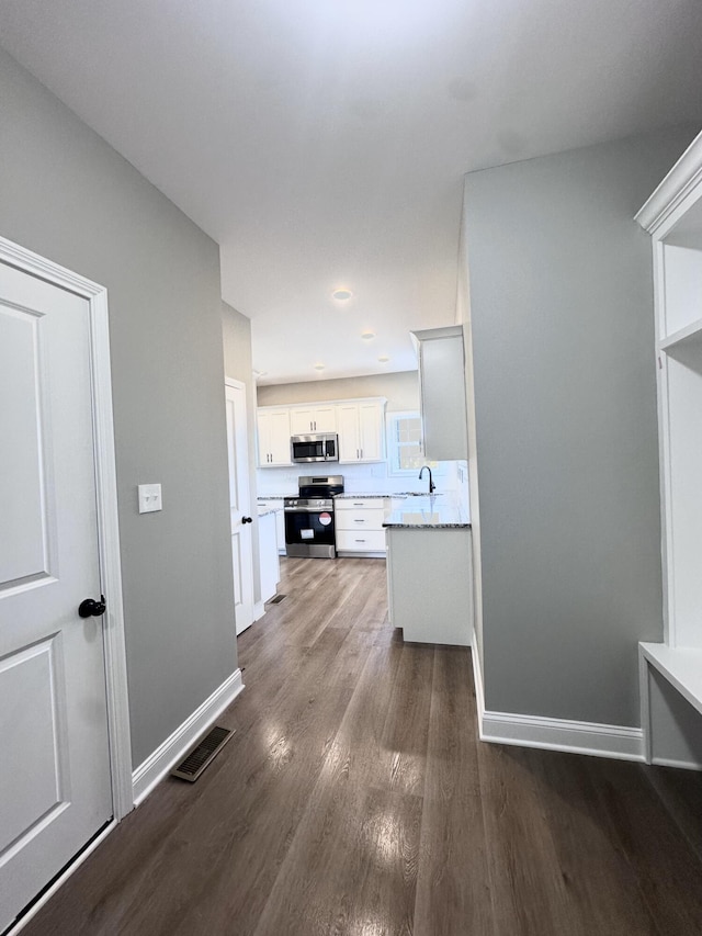 kitchen featuring stainless steel appliances, white cabinetry, dark hardwood / wood-style floors, and sink