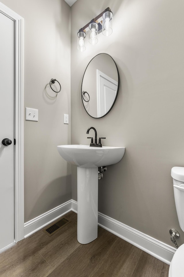 bathroom featuring toilet, wood finished floors, visible vents, and baseboards