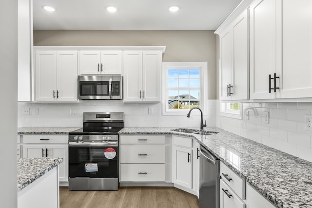 kitchen featuring light wood finished floors, white cabinetry, stainless steel appliances, and a sink