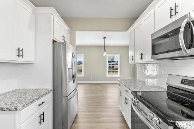 kitchen with appliances with stainless steel finishes, white cabinetry, and light stone countertops