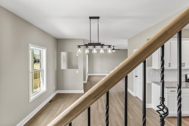 stairs with a wealth of natural light, visible vents, baseboards, and wood finished floors