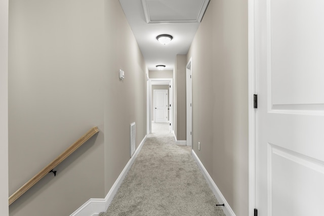 hall featuring baseboards, an upstairs landing, visible vents, and light colored carpet