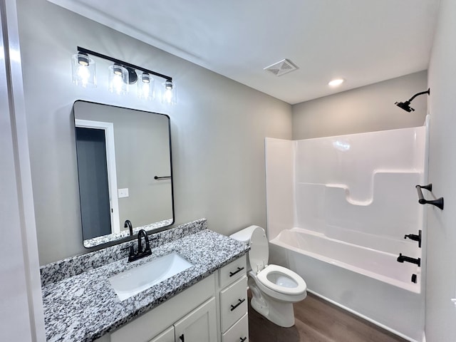 full bathroom featuring hardwood / wood-style flooring, bathing tub / shower combination, vanity, and toilet