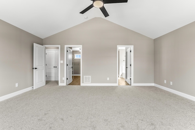 unfurnished bedroom featuring ensuite bathroom, light carpet, visible vents, baseboards, and vaulted ceiling