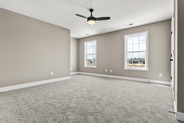 carpeted empty room featuring a ceiling fan, visible vents, and baseboards