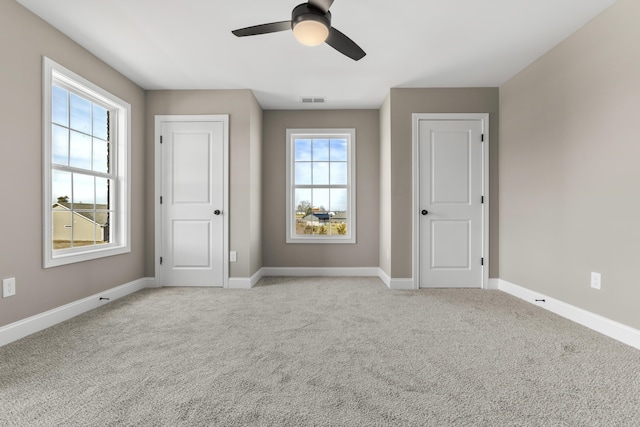 interior space featuring a ceiling fan, light colored carpet, visible vents, and baseboards