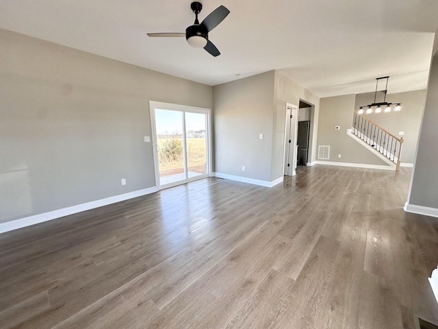 interior space with ceiling fan with notable chandelier and light hardwood / wood-style floors