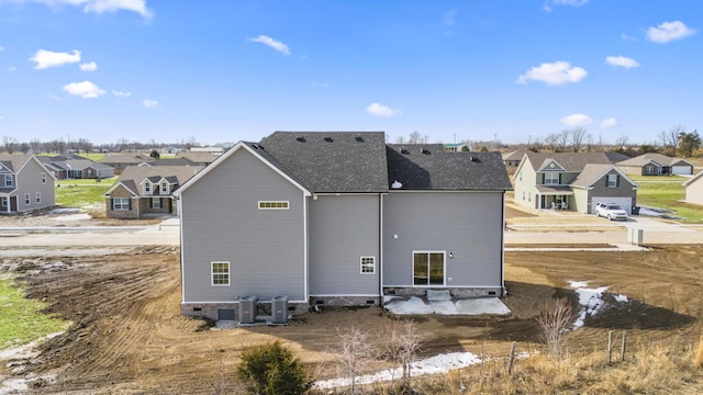 back of house with central AC, a shingled roof, and a residential view