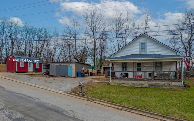 view of front of house featuring a front yard, a storage unit, and covered porch