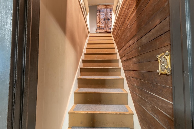 stairs featuring wood walls