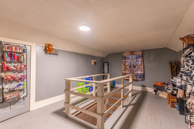 interior space with wood-type flooring, lofted ceiling, and a textured ceiling