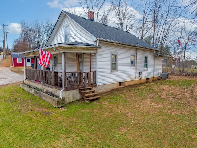 rear view of property featuring cooling unit, covered porch, and a lawn