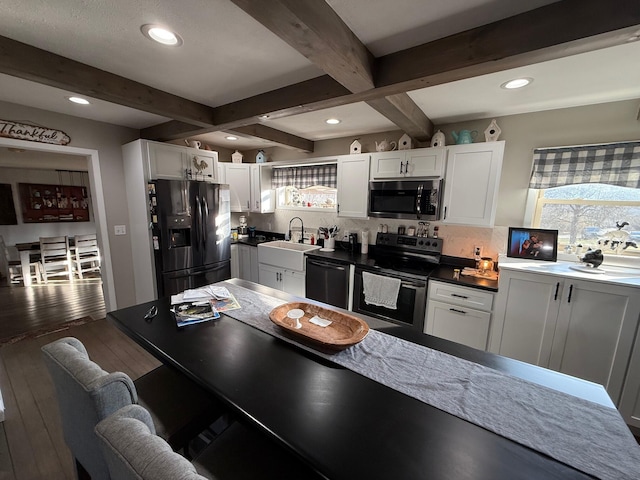 kitchen with beamed ceiling, appliances with stainless steel finishes, sink, and white cabinets