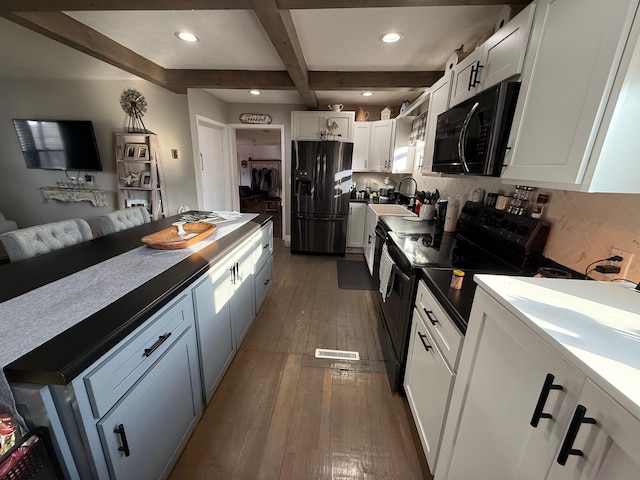 kitchen with beam ceiling, coffered ceiling, black appliances, white cabinets, and dark hardwood / wood-style flooring