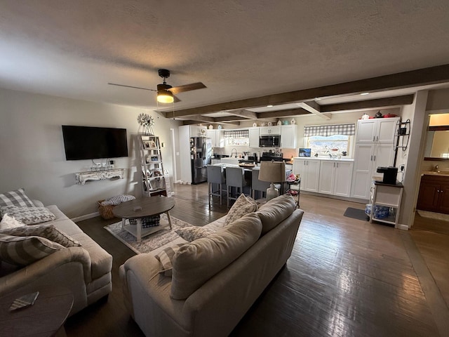 living room featuring beam ceiling, ceiling fan, a textured ceiling, and dark hardwood / wood-style flooring