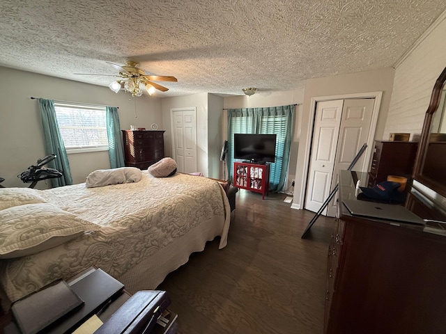 bedroom featuring dark hardwood / wood-style flooring, two closets, a textured ceiling, and ceiling fan