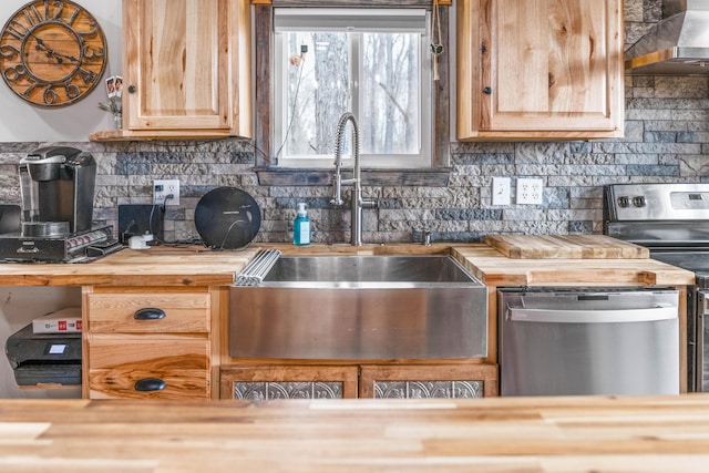 kitchen featuring butcher block countertops, wall chimney range hood, sink, range, and stainless steel dishwasher