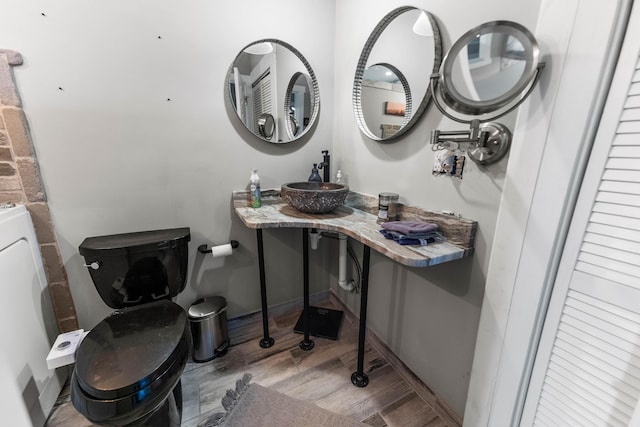 bathroom with hardwood / wood-style flooring, vanity, toilet, and washer / dryer