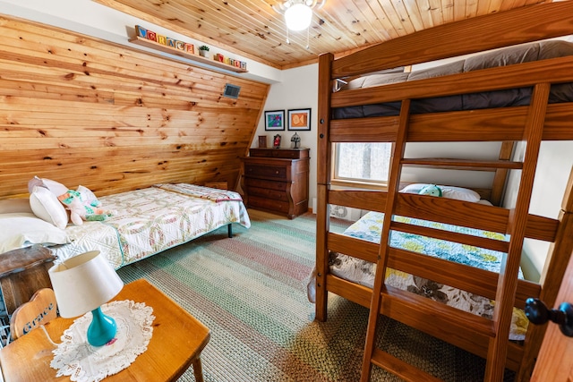 carpeted bedroom with wood ceiling and wood walls