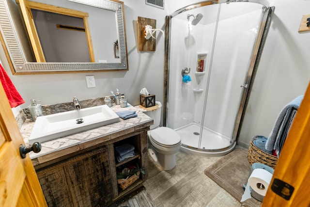 bathroom with hardwood / wood-style floors, vanity, toilet, and a shower with shower door