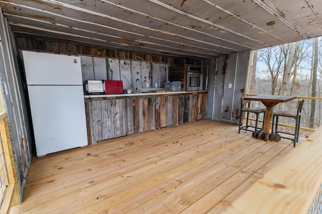 basement with sink, light hardwood / wood-style flooring, and white fridge