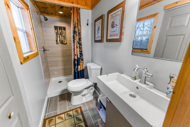 bathroom featuring wood finished floors, toilet, a sink, baseboards, and tiled shower