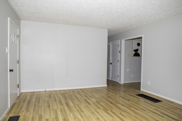 unfurnished room featuring light hardwood / wood-style flooring and a textured ceiling